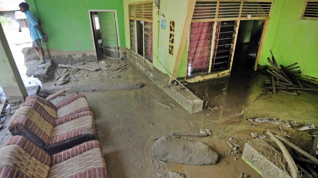 Warga berada disekitar rumah yang rusak dan terendam lumpur akibat diterjang banjir bandang di Desa Poi, Kabupaten Sigi, Sulawesi Tengah, Minggu (8/12). [ANTARA FOTO/Mohamad Hamzah]
