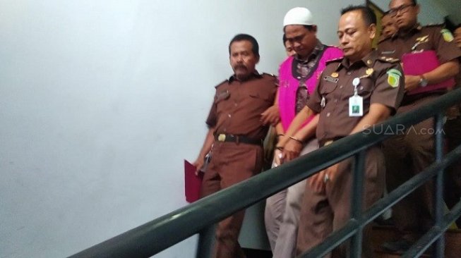 Eks Kades Karangasih, Asep Maulana saat digiring petugas untuk ditahan selama 20 hari ke depan. (Suara.com/M. Yacub).