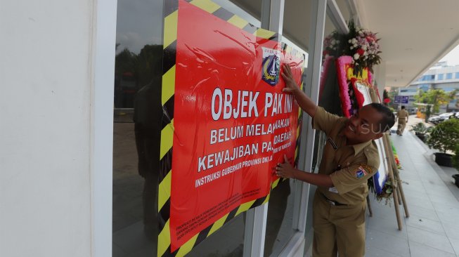 Petugas Badan Pajak dan Restribusi Daerah (BPRD) DKI Jakarta berada di sekitar stiker 'Objek Pajak' saat Supervisi pencegahan pajak di kantor Banteng Muda, Benhil, Jakarta Pusat, Senin (9/12). [Suara.com/Angga Budhiyanto]