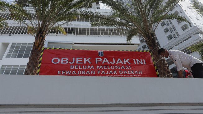 Petugas Badan Pajak dan Restribusi Daerah (BPRD) DKI Jakarta berada di sekitar stiker 'Objek Pajak' saat Supervisi pencegahan pajak di kantor Banteng Muda, Benhil, Jakarta Pusat, Senin (9/12). [Suara.com/Angga Budhiyanto]