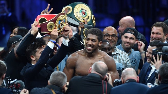 Petinju Inggris, Anthony Joshua (tengah), merayakan keberhasilannya menjadi juara dunia tinju kelas berat WBA (Super), WBO, IBO dan IBF, usai mengalahkan Andy Ruiz dalam pertarungan di Diriyah Arena, Arab Saudi, Sabtu (7/12/2019) malam waktu setempat. [AFP/Fayez Nureldine]