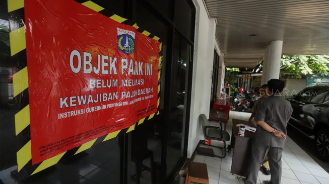 Petugas Badan Pajak dan Restribusi Daerah (BPRD) DKI Jakarta berada di sekitar stiker 'Objek Pajak' saat Supervisi pencegahan pajak di kantor Banteng Muda, Benhil, Jakarta Pusat, Senin (9/12). [Suara.com/Angga Budhiyanto]