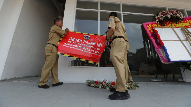 Petugas Badan Pajak dan Restribusi Daerah (BPRD) DKI Jakarta berada di sekitar stiker 'Objek Pajak' saat Supervisi pencegahan pajak di kantor Banteng Muda, Benhil, Jakarta Pusat, Senin (9/12). [Suara.com/Angga Budhiyanto]