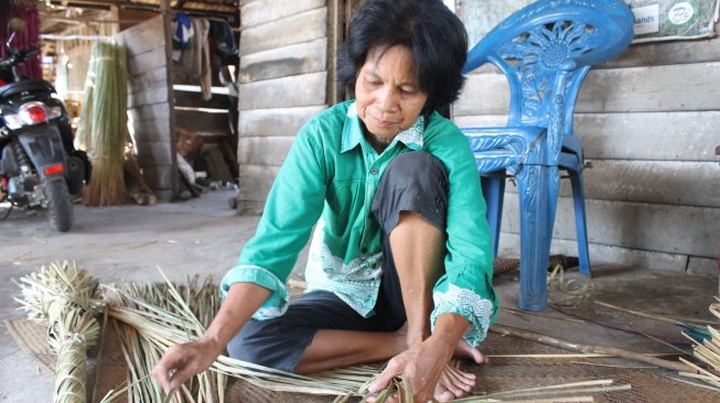 Rusmi (50) warga Desa Menang Raya, Kecamatan Pedamaran Kabupaten Ogan Komering Ilir (OKI), Sumatera Selatan (Sumsel), menganyam tikar purun di sela waktu luang, Kamis (08/05/2019). Mengayam purun menjadi tradisi warga Pedamaran secara turun temurun, sekaligus menjadi penopang ekonomi warga setempat. [Foto: Ibrahim Arsyad]