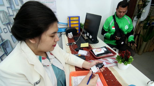 Petugas apotek Gancang Aron memesan ojek daring untuk mengantar obat ke pasien kurang mampu di RSUD Blambangan, Banyuwangi, Jawa Timur, Rabu (11/12). [ANTARA FOTO/Budi Candra Setya]