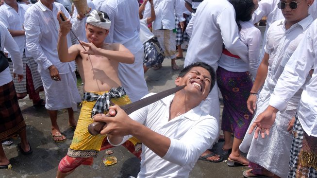 Dua warga yang kesurupan menusukkan keris ke bagian wajahnya dan dadanya saat upacara "Nangluk Merana" atau tolak bala di Desa Adat Kuta, Badung, Bali, Senin (16/12). [ANTARA FOTO/Nyoman Hendra Wibowo]