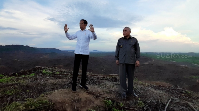 Presiden Joko Widodo (kiri) berbincang dengan Gubernur Kalimantan Timur Isran Noor (kanan) saat meninjau lokasi rencana ibu kota baru di Sepaku, Penajam Paser Utara, Kalimantan Timur, Selasa (17/12). [Suara.com/Ummy Hadyah Saleh]