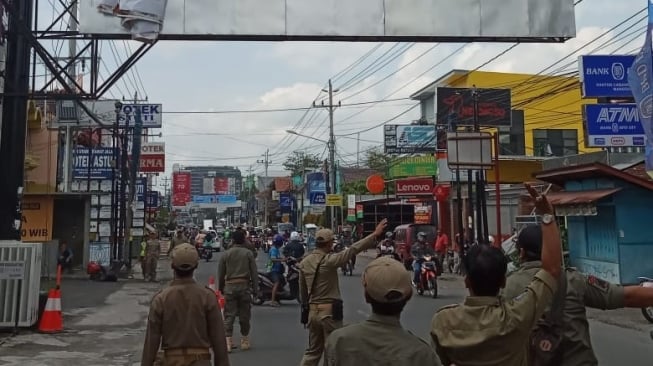 Petugas Satpol PP Kabupaten Sleman melakukan pembongkaran baliho raksasa yang melintang di Jalan Kaliurang, Selasa (17/12/2019). [Istimewa]