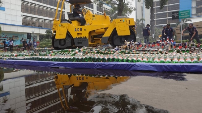 Petugas gunakan alat berat memusnahkan barang bukti minuman keras di Kantor Bea Cukai, Rawamangun, Jakarta, Kamis, (19/12). [Suara.com/Angga Budhiyanto]