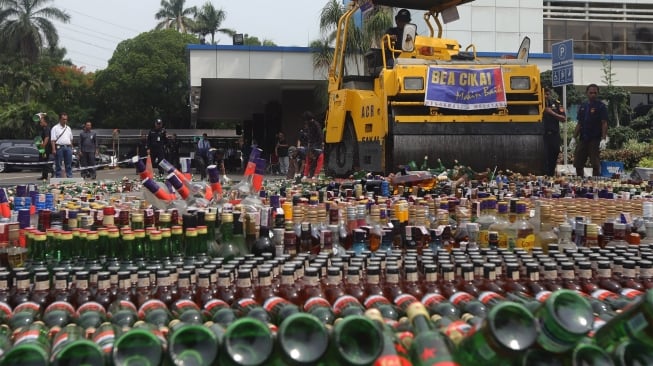 Petugas gunakan alat berat memusnahkan barang bukti minuman keras di Kantor Bea Cukai, Rawamangun, Jakarta, Kamis, (19/12). [Suara.com/Angga Budhiyanto]