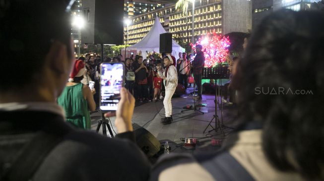 Penyanyi melantunkan lagu lagu natal dalam acara Christmas Carol di Bundaran Hotel Indonesia, Kamis (19/12). [Suara.com/Alfian Winanto]