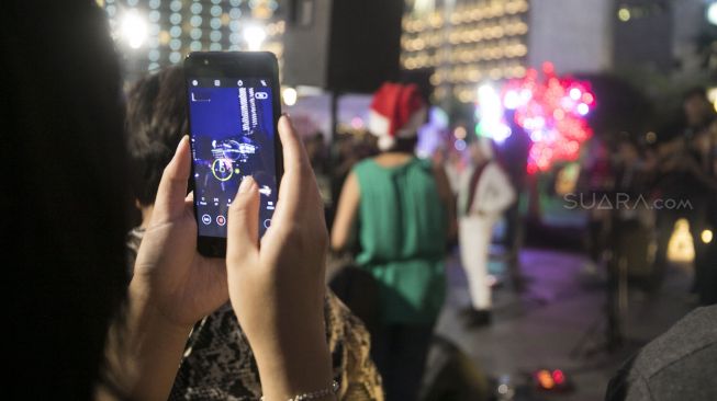 Salah seorang penonton yang tengah merekam acara christmas carol secara live dengan smartphonenya di Bundaran Hotel Indonesia, Kamis (19/12)