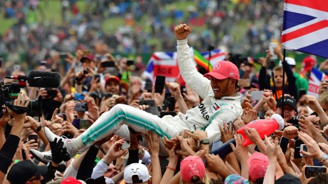 Pebalap Inggris dari tim Mercedes, Lewis Hamilton, diarak oleh kru timnya usai memenangi balapan F1 GP Inggris di Sirkuit Silverstone, Minggu (14/7/2019). [AFP/Andrej Isakovic]