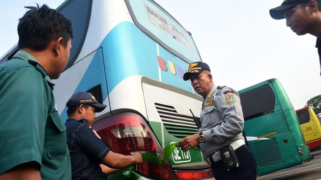 Petugas Dinas Perhubungan DKI Jakarta melepas stiker yang menutupi lampu sein bus saat pemeriksaan kelaikan angkutan di Terminal Kampung Rambutan, Jakarta, Jumat (20/12). [ANTARA FOTO/Indrianto Eko Suwarso]