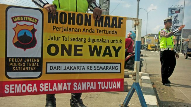 Polisi memasang papan penutupan akses masuk gerbang tol arah Jakarta di pintu keluar tol Adiwerna, Kabupaten Tegal, Jawa Tengah, Sabtu (21/12). [ANTARA FOTO/Oky Lukmansyah]