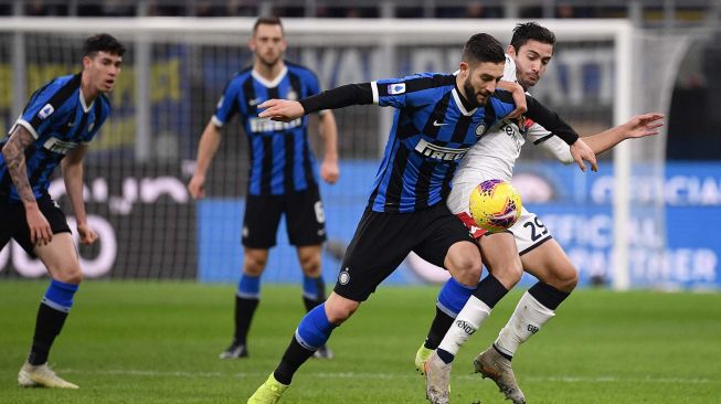 Gelandang Inter Milan Roberto Gagliardini berebut bola dengan gelandang Genoa Francesco Cassata selama pertandingan sepak bola Serie A Italia antara Inter Milan melawan Genoa di Stadion Giuseppe Meazza, Milan, Italia, Minggu (22/12) dini hari WIB. [Marco Bertorello / AFP]