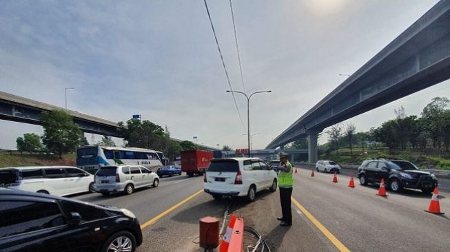 Polisi memberlakukan contraflow jalan tol Japek arah Cikampek, Minggu (22/12/2019). (Suara.com/Yacub)