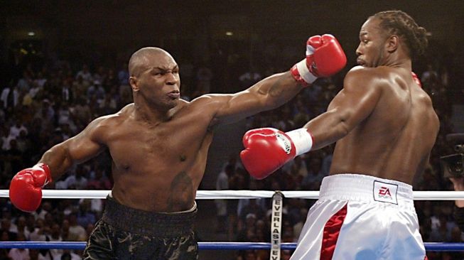 Petinju berjuluk Leher Beton, Mike Tyson (kiri), melayangkan pukulan ke wajah lawannya, Lennox Lewis, dalam duel di The Pyramid, Memphis, Amerika Serikat, Sabtu (8/6/2002). [AFP]