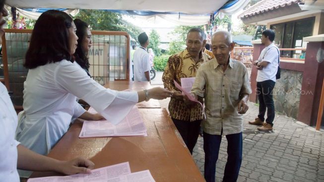 Jemaat gereja yang datang diberikan selebaran prosesi Misa Malam Natal di Gereja Santo Servatius Kampung Sawah, Bekasi Jawa Barat, Selasa (24/12) malam.