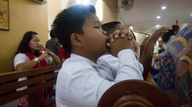 Para Jamaat cilik yang khusyuk berdoa saat misa natal khusus anak-anak di Gereja Santo Servatius, Kampung Sawah, Bekasi, Rabu (25/12). (Suara.com/Alfian Winanto)