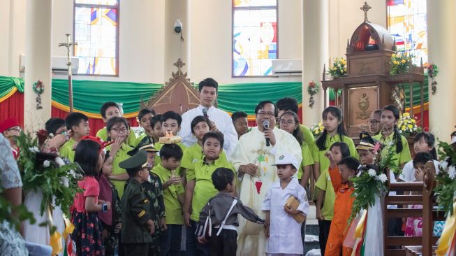 Para Jamaat cilik Gereja Santo Servatius bersama dengan Pastor Yohannes Wartaya Winangun saat Misa natal khusus anak-anak di Gereja Santo Servatius, Kampung Sawah, Bekasi, Rabu (25/12). (Suara.com/Alfian Winanto)

