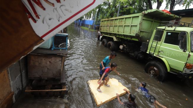 Sejumlah anak bermain di jalan yang terendam banjir di kawasan Sunter, Jakarta Utara, Rabu (25/12). [Suara.com/Angga Budhiyanto]