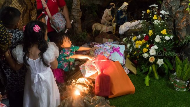 Seorang Jamaat cilik yang memberikan kado kepada Yesus didepan diorama gua lahirnya Yesus prosesi misa natal khusus anak-anak di Gereja Santo Servatius, Kampung Sawah, Bekasi, Rabu (25/12). (Suara.com/Alfian Winanto)
