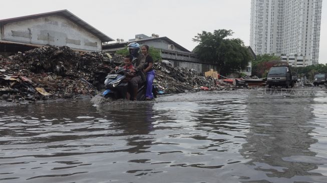 Pengendara melintas di jalan yang terendam banjir di kawasan Sunter, Jakarta Utara, Rabu (25/12).  [Suara.com/Angga Budhiyanto]