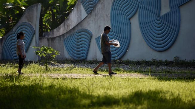 Korban selamat joni dan putrinya menaburkan bunga saat memperingati 15 tahun musibah gempa dan tsunami di kuburan Massal Siron, Aceh, Kamis (26/12). [CHAIDEER MAHYUDDIN / AFP]