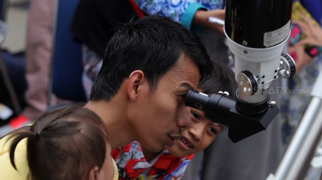 Pengunjung menggunakan teleskop untuk melihat gerhana matahari cincin dari Planetarium Taman Ismail Marzuki, Jakarta, Kamis (26/12). [Suara.com/Angga Budhiyanto]