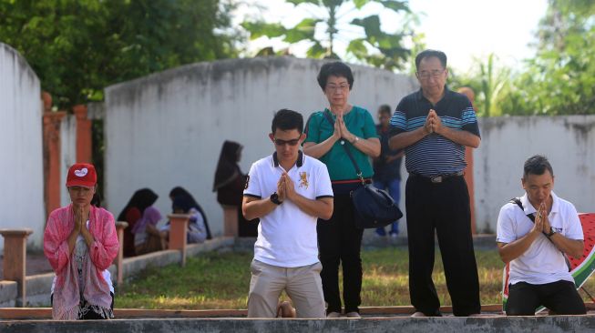 Sejumlah umat muslim bersama warga keturunan Tionghoa melaksanakan doa bersama saat berziarah ke kuburan massal korban gempa dan gelombang tsunami di Desa Suak Indrapuri, Johan Pahlawan, Aceh Barat, Aceh, Kamis (26/12). [ANTARA FOTO/Syifa Yulinnas]