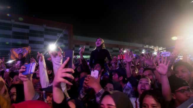 Penonton yang sedang mengabadikan momen dengan smartphone nya saat Didi Kempot tampil di Panggung Big Bang Festival Jiexpo Kemayoran, Jakarta Pusat, Jumat (27/12) malam. [Suara.com/Alfian Winanto]

