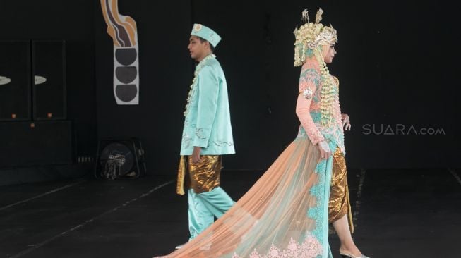 Model yang berjalan di catwalk dalam pagelaran pesona Budaya Jawa Barat, di Panggung Kesenian anjungan Jawa Barat, Taman Mini Indonesia Indah, Jakarta Timur (29/12). [Suara.com/Alfian Winanto]