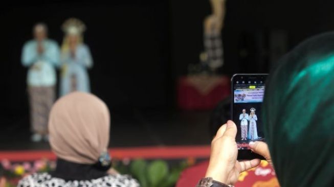 Pengunjung mengambil foto model yang berjalan di catwalk dalam pagelaran pesona Budaya Jawa Barat, di Panggung Kesenian anjungan Jawa Barat, Taman Mini Indonesia Indah, Jakarta Timur (29/12).(suara.com/Alfian Winanto)