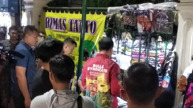 Presiden Joko Widodo (berjaket merah) nampak membeli kaus bersama anak bungsunya, Kaesang Pengarep di Kilometer 0, Malioboro, Yogyakarta, Senin (30/12/2019). (SuaraJogja.id/Baktora)