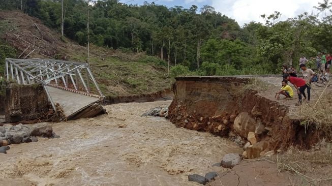 Warga mengamati jembatan penghubung Kecamatan Mulak Ulu dengan Mulak Sebingkai, Kabupaten Lahat yang terputus akibat banjir bandang di Mulak Ulu, Lahat, Sumatera Selatan, Senin (30/12). [ANTARA FOTO/M Rega Derbiansyah]