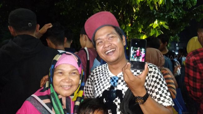 Wisatawan asal Tasikmalaya, Yoga Nugraha bersama keluarga menunjukkan foto bersama Presiden Joko Widodo saat berkunjung ke Kilometer 0, Malioboro, Yogyakarta, Senin (30/12/2019). (SuaraJogja.id/Baktora)