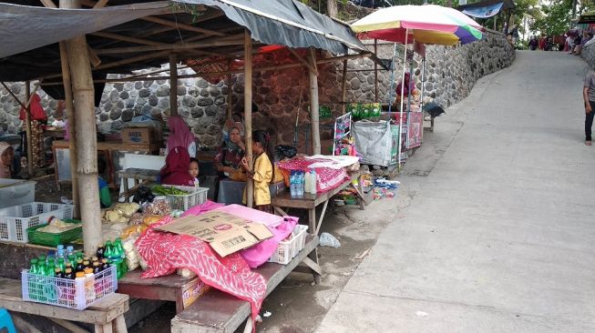 Sejumlah pedagang menggelar barang dagangannya di sepanjang pintu masuk Bendung Kamijoro di wilayah Pajangan, Bantul, Selasa (31/12/2019). - (SUARA/Baktora)