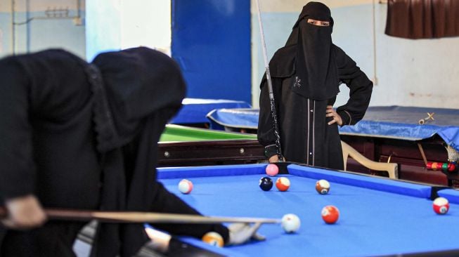 Seorang wanita bercadar mengamati lawannya selama kejuaraan biliar lokal di sebuah gedung olahraga di ibu kota Sanaa, Yaman, Senin (16/12). [Mohammed HUWAIS / AFP]
