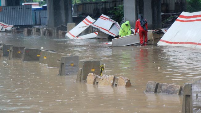 Petugas membetulkan pembatas jalan yang diterjang banjir di jalan HR Rasuna Said, Jakarta Selatan, Rabu (1/1). [Suara.com/Oke Atmja]