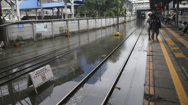 Warga memperhatikan rel kereta api yang terendam banjir di Stasiun KA Tanah Abang, Jakarta, Rabu (1/1/).[ANTARA FOTO/Nova Wahyudi]