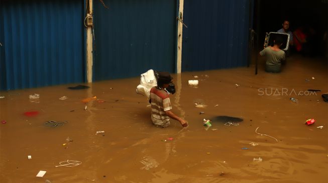 Pedagang menyelamatkan barang dagangannya dari banjir yang merendam Pasar Cipulir, Jakarta Selatan, Rabu (1/1). [Suara.com/Angga Budhiyanto]