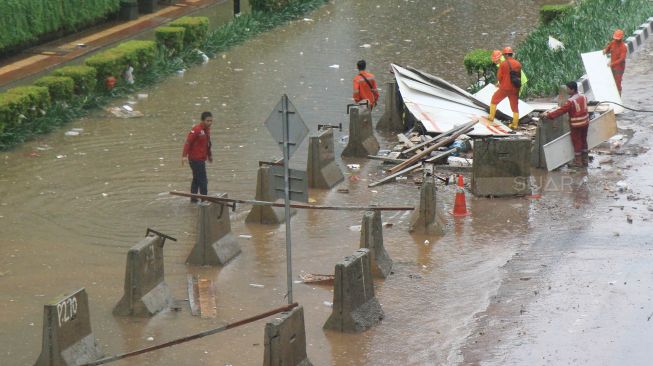 Petugas membetulkan pembatas jalan yang diterjang banjir di jalan HR Rasuna Said, Jakarta Selatan, Rabu (1/1). [Suara.com/Oke Atmaja]