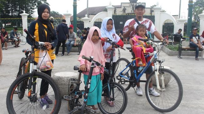 Keluarga Amon Kurniawan, warga Dusun Kajen, Desa Bangunjiwo, Kecamatan Kasihan, Kabupaten Bantul, sampai di Titik Nol Kilometer Kota Jogja untuk merayakan tahun baru dengan bersepeda, Rabu (1/1/2020) pagi. - (SUARA/Baktora)