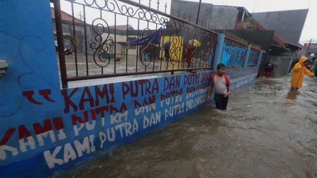 Sejumlah warga berada di jalan yang terendam banjir di kawasan Jatipadang, Pasar Minggu, Jakarta Selatan, Rabu (1/1). [Suara.com/Angga Budhiyanto]