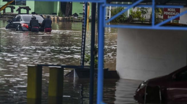 Warga mengevakuasi mobil di pool taksi Kramat Jati, Jalan Raya Pondok Gede, Jakarta, Rabu (1/1). [ANTARA FOTO/Galih Pradipta]