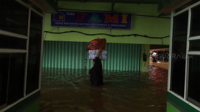 Pedagang menyelamatkan barang dagangannya dari banjir yang merendam Pasar Cipulir, Jakarta Selatan, Rabu (1/1). [Suara.com/Angga Budhiyanto]
