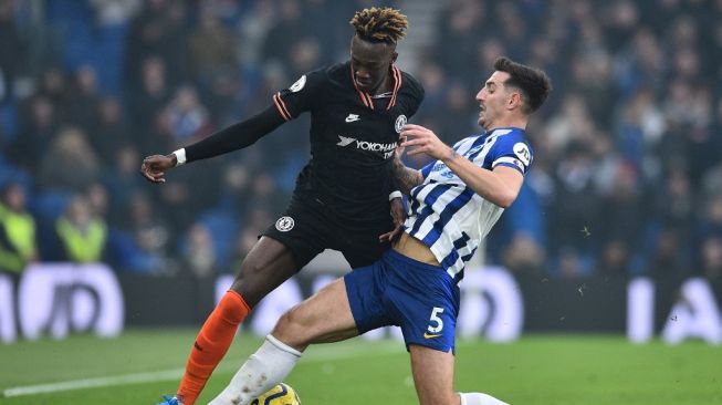 Penyerang Chelsea, Tammy Abraham (kiri) berduel dengan bek Brighton, Lewis Dunk pada laga Liga Inggris 2019/2020 di Amex Stadium, Rabu (1/1/2020). [Glyn KIRK / AFP]