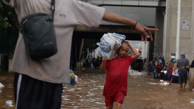 

Pedagang menyelamatkan barang dagangannya dari banjir yang merendam Pasar Cipulir, Jakarta Selatan, Rabu (1/1). [Suara.com/Angga Budhiyanto]

