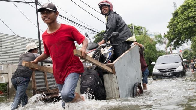 Ojek gerobak mendorong penumpang diatasnya untuk menyeberang Persimpangan Puri Kembangan, Kembangan Pasar Minggu, Jakarta Barat, Jumat (3/1).  [Suara.com/Alfian Winanto]